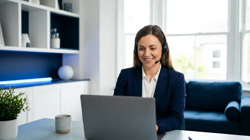 IT support specialist wearing a headset, helping a customer remotely from a laptop